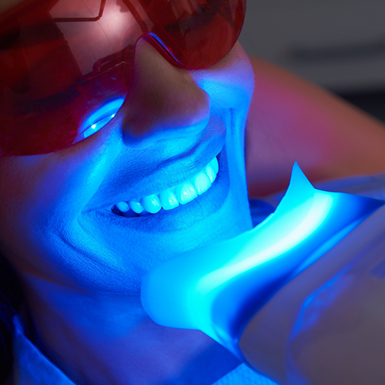 Woman in dental chair receiving professional teeth whitening