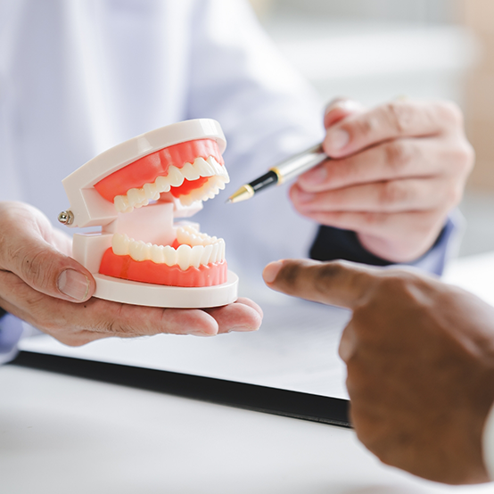 Dentist showing a model of a denture to a patient