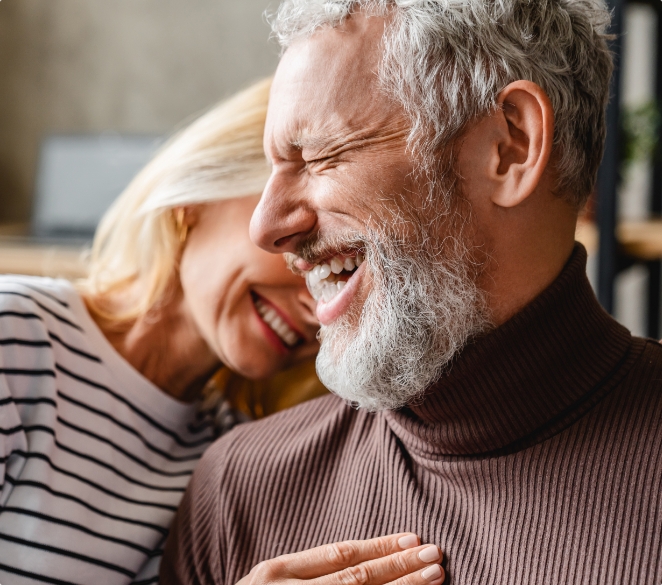 Senior man and woman laughing while hugging