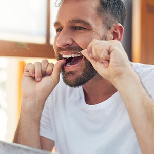 Patient flossing his teeth in bathroom