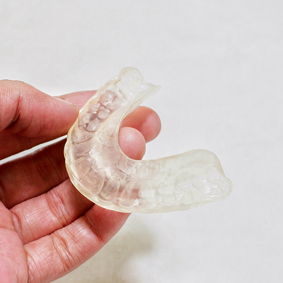 Hand holding a clear occlusal splint