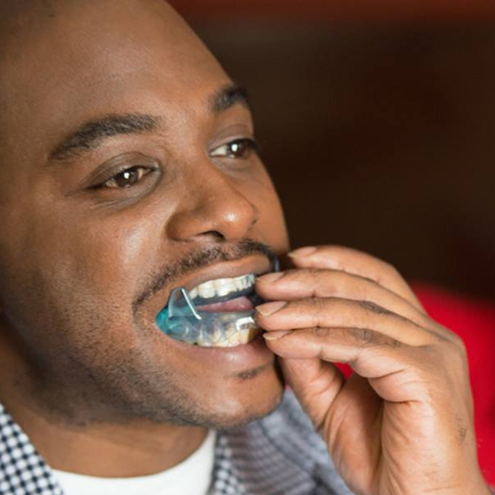 Man placing an oral appliance in his mouth with sleep apnea treatment