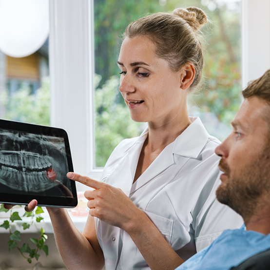 Dentist showing a patient an x ray of his teeth before wisdom tooth extractions in Jupiter