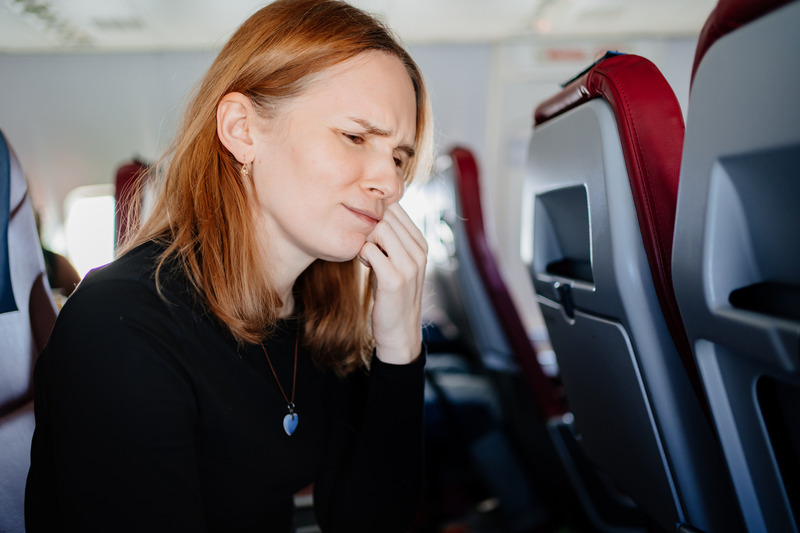 Patient holding their cheek on a plane due to toothaches